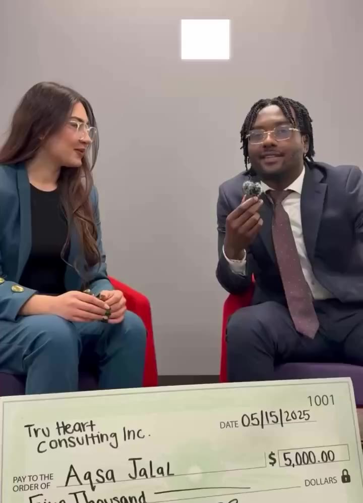Aqsa Jalal seated beside a teammate, her $5,000 check in front of them