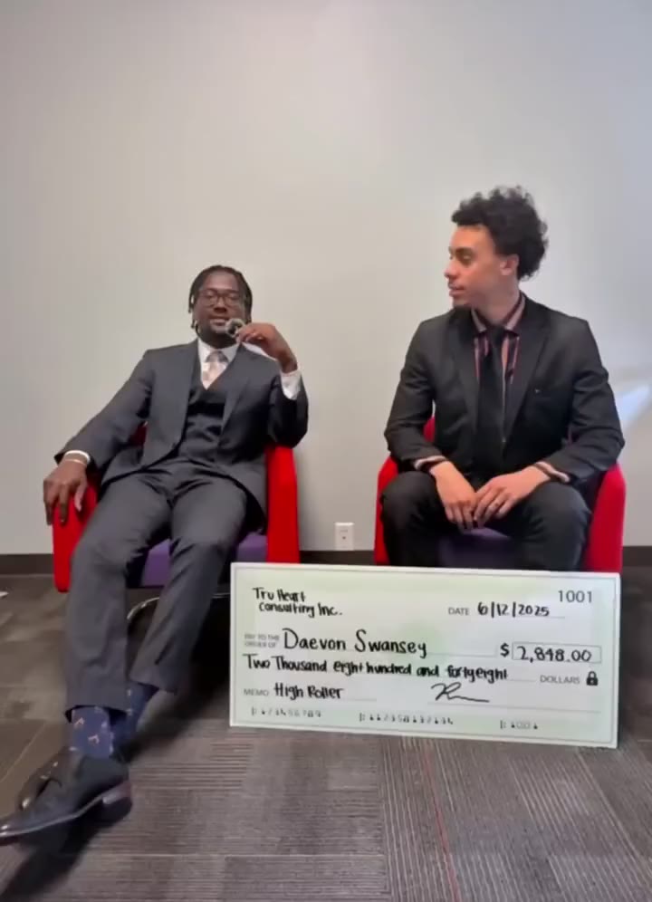 Daevon Swansey seated beside a teammate, his check in front of them